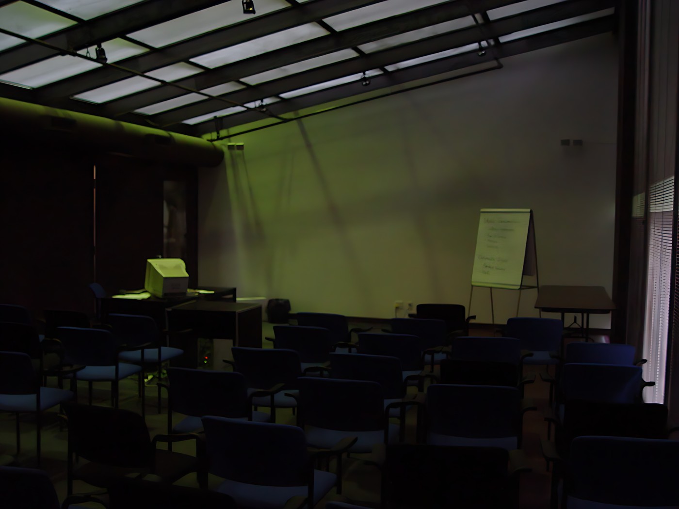 Empty lecture hall with rows of blue chairs facing the front of the room